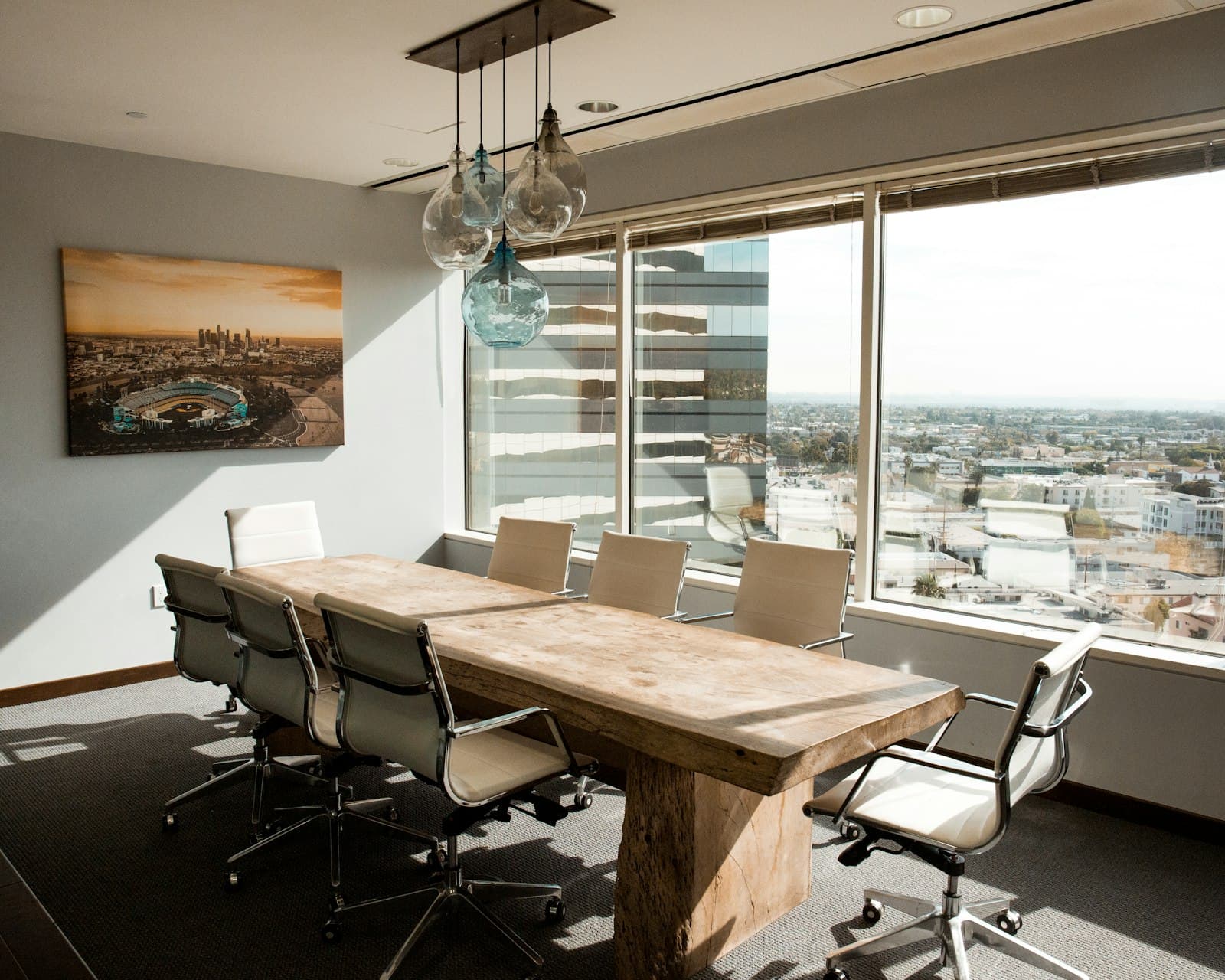 An empty boardroom with a long timber table and daylight across the city.