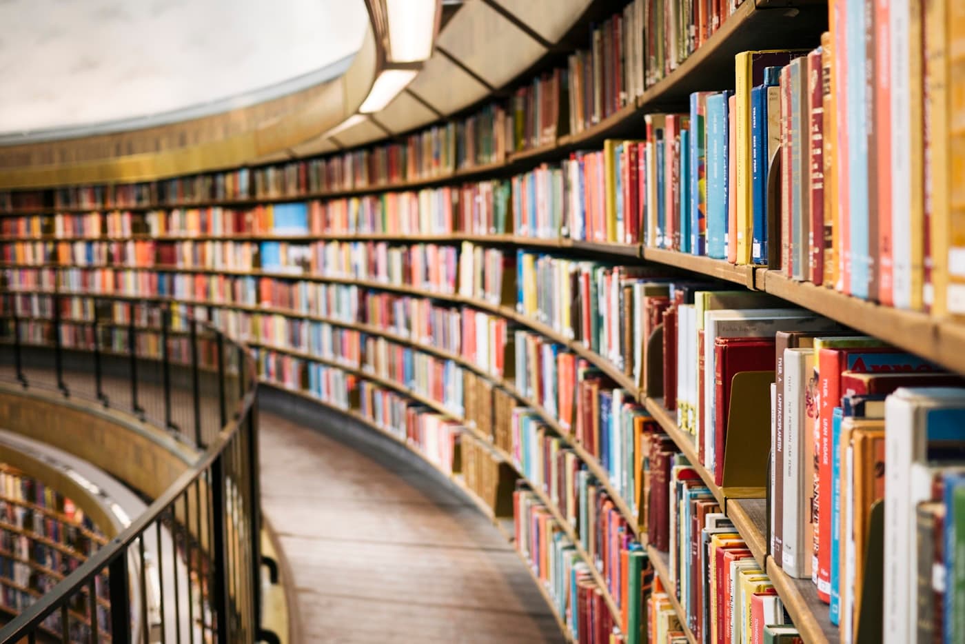 A curved library gallery of bound volumes in warm light.
