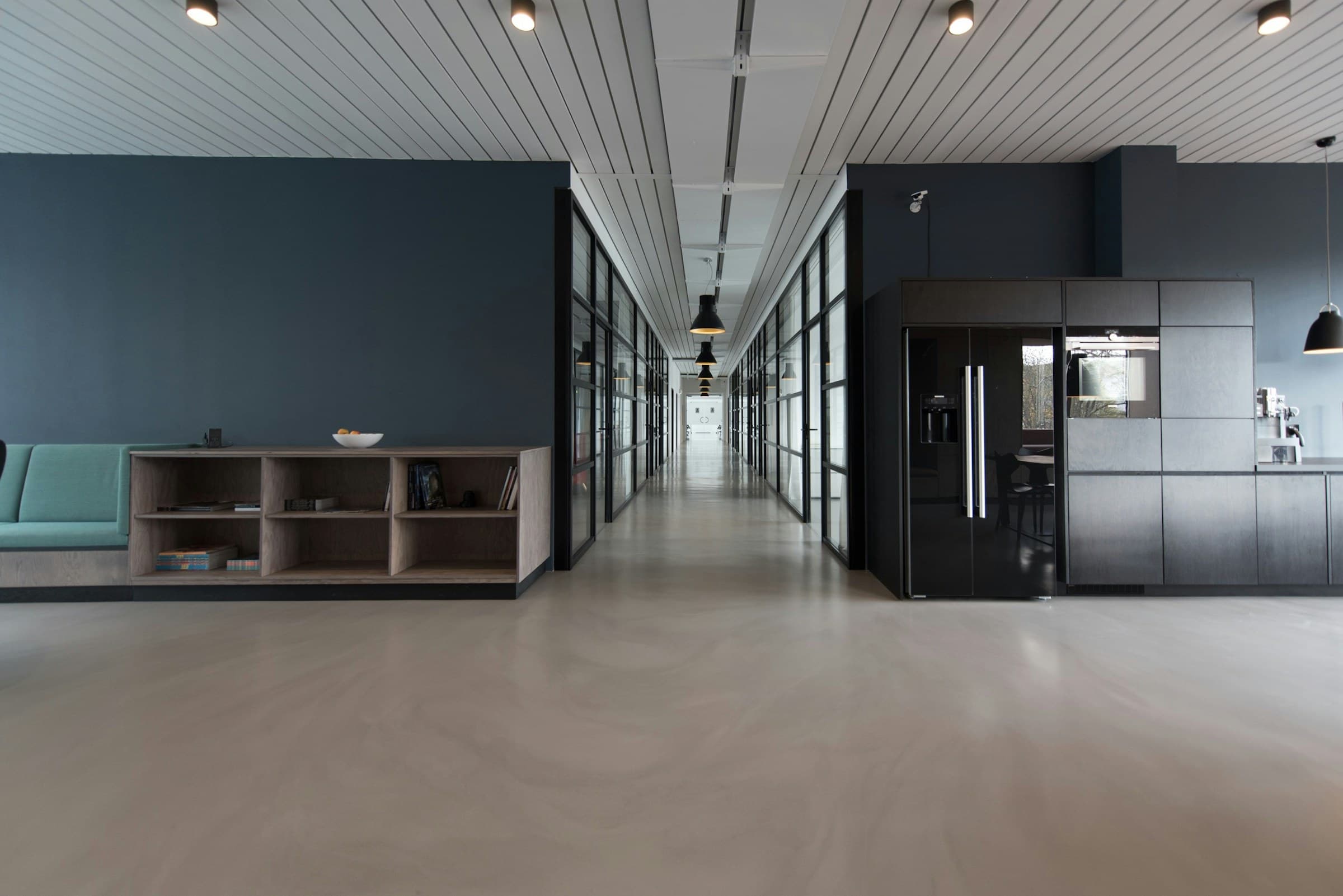 A contemporary Amsterdam office interior with a long table, stone floor and tall windows.